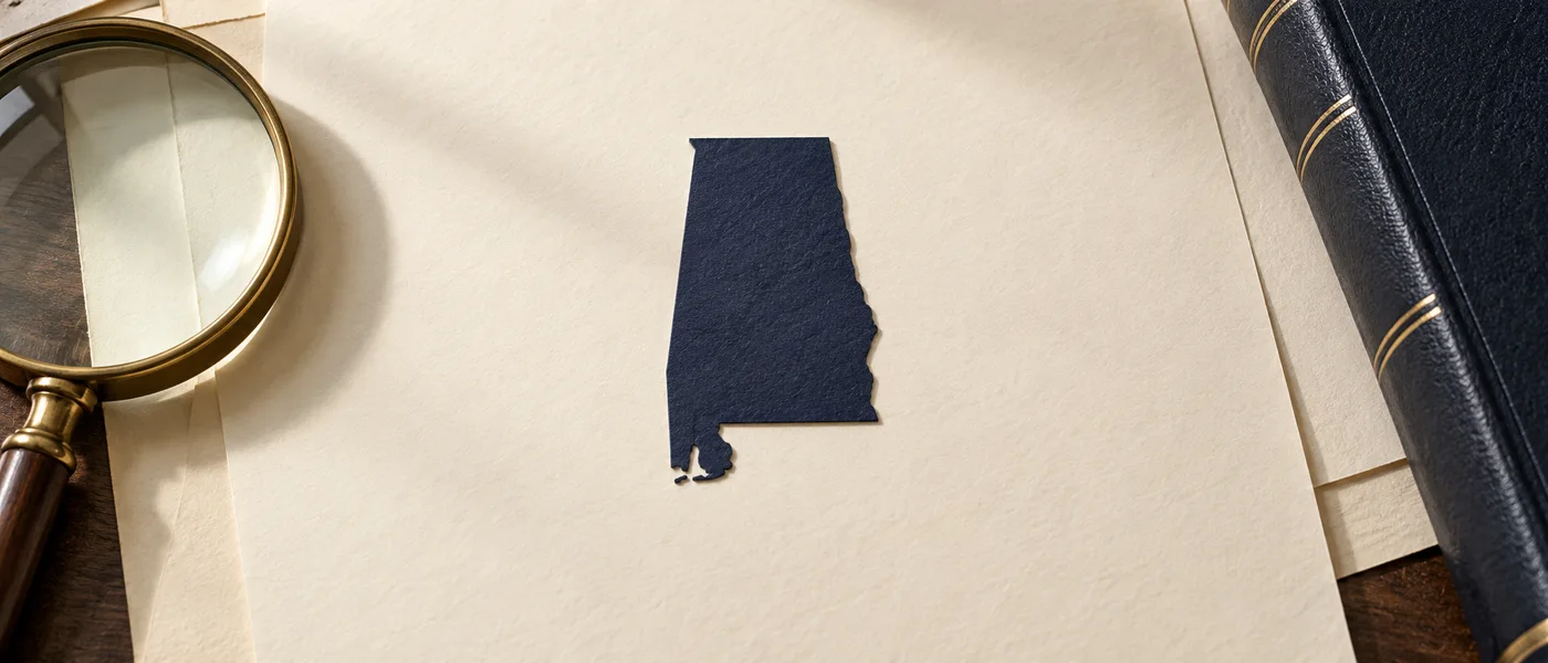Editorial illustration of the Alabama state outline on legal documents beside a magnifying glass.